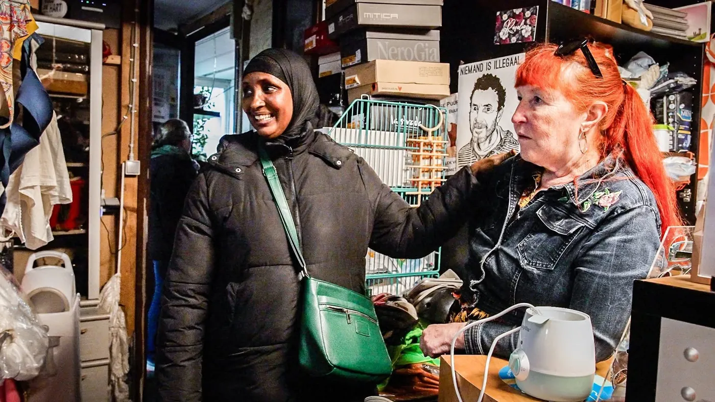 Een bezoeker en een vrijwilliger lachen samen in de weggeefwinkel